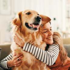 A woman is hugging a golden retriever dog.