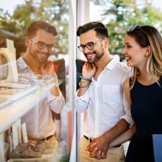 A man and woman are shopping together, holding hands and smiling.