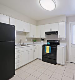 a kitchen with white cabinets and black appliances