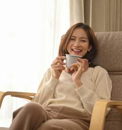 A woman is sitting in a chair holding a cup.