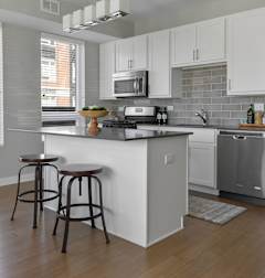 A kitchen with white cabinets and a wooden floor.