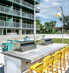 a large outdoor kitchen with two grills and yellow chairs