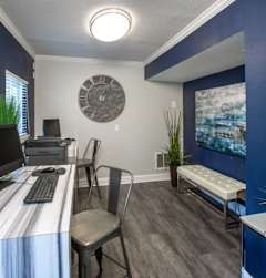 A room with a desk, chair, and a clock on the wall.