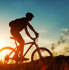 a man riding a bike on a hill at sunset