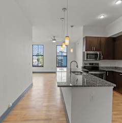 A kitchen with a black counter top and a refrigerator.