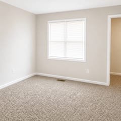 A room with a window and carpeted floor.