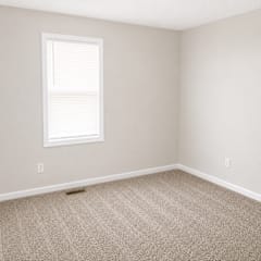 A room with a carpeted floor and a window with blinds.