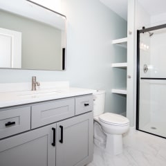 a bathroom with a white sink and toilet next to a shower with a glass door