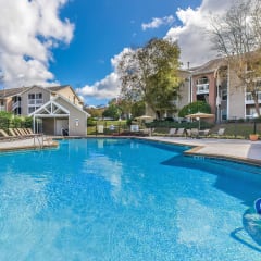 a swimming pool with lounge chairs and umbrellas in front of a house at Arbors at Windsor Lake, South Carolina, 29223