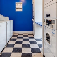 a laundry room with white washers and dryers and a blue wall