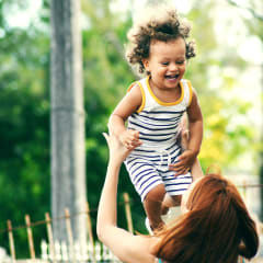a woman holding a little girl up in the air