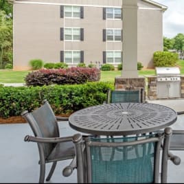 a patio with a table and chairs in front of an apartment complex