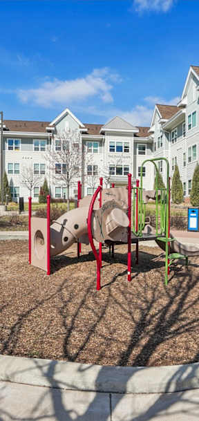 A playground with a slide and a red and green swing set.