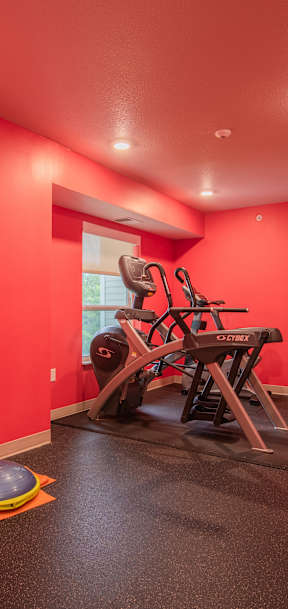 A red room with a gym set up including weights and a bench press.