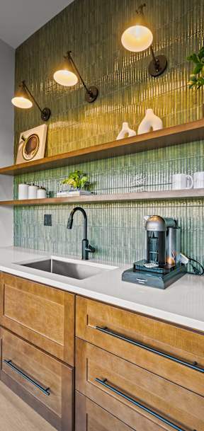 A modern kitchen with wooden drawers and a green backsplash.