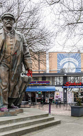 A statue of a man stands in front of a building with a sign that says "Stone.".