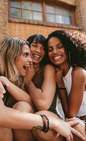 Three friends are sitting together and laughing.