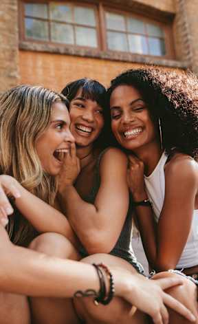Three friends are sitting together and laughing.