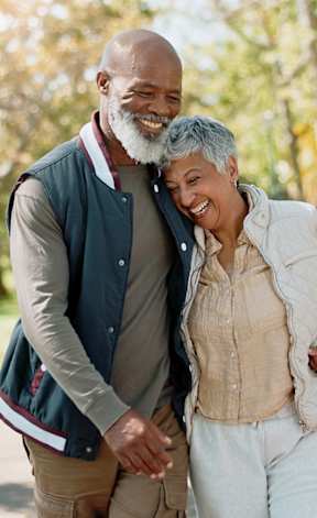 An older couple is walking together in a park.