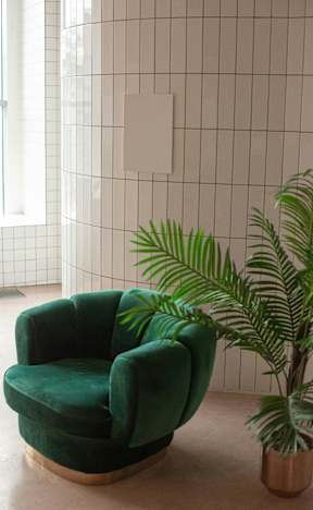 A green chair is in front of a tiled wall.