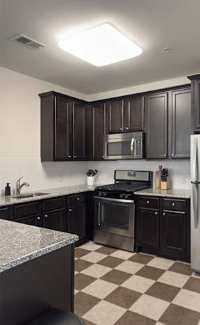A kitchen with black cabinets and a checkered floor.