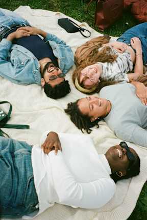 Four people lying on a blanket outdoors.