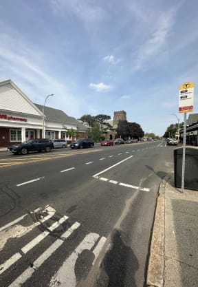 a city street with cars parked on the side of the road and a castle in the background