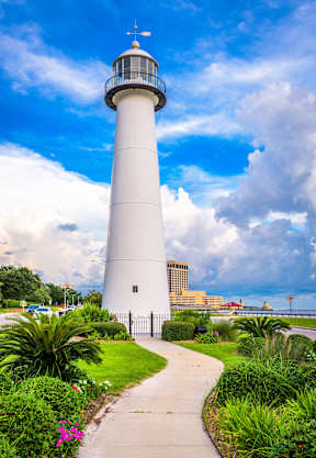 A white lighthouse with a walkway leading to it.