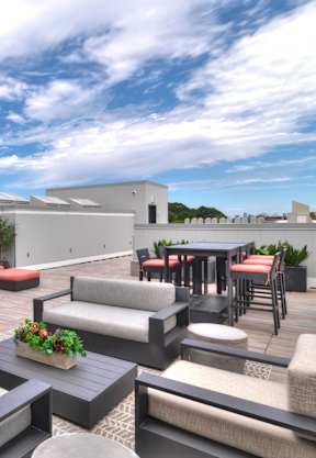 A patio with red and grey furniture and a white building in the background.