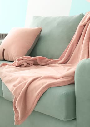 a green couch with a pink blanket on top of it