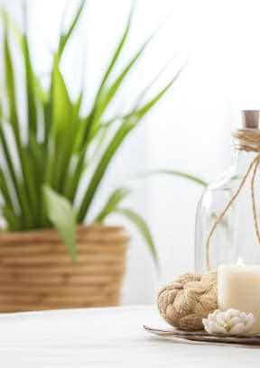 a pile of white towels on a table with a bottle of lotion and candles