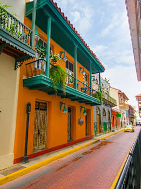 A street with buildings on either side and a car on the road.