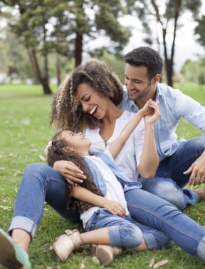 a man and woman sitting on the grass with a child