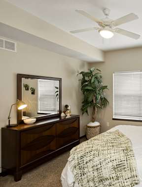 A bedroom with a bed, a dresser, and a ceiling fan.