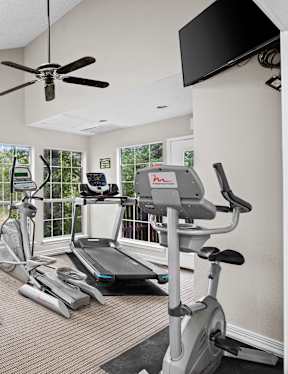 A home gym with a variety of equipment including a treadmill, stationary bike, and weight machines.