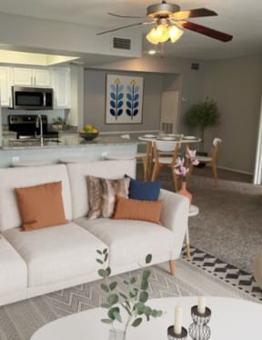 a living room with a ceiling fan and large windows