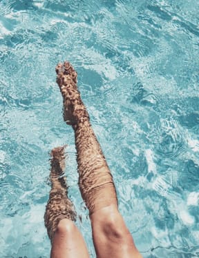 a woman laying in a pool with her legs in the water