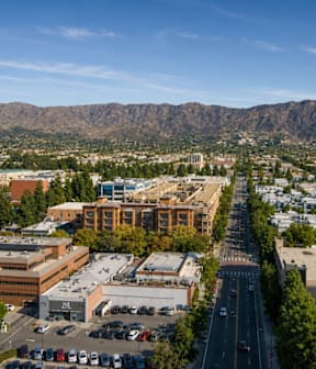 A city street with cars parked on the side and buildings on both sides.