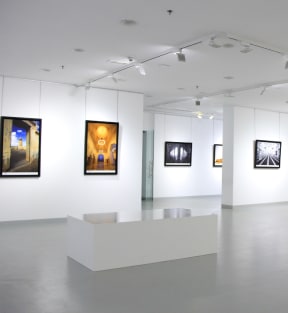 a gallery with paintings on the wall and a table in the middle