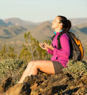 a woman sitting on a rock with a backpack