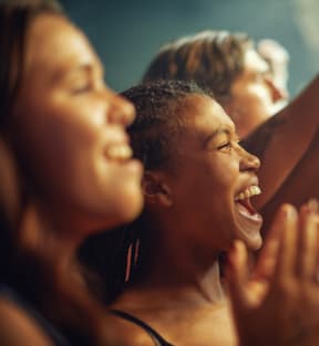 a group of women laughing and cheering at a concert
