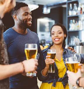 A group of people are toasting with beer glasses in a bar.