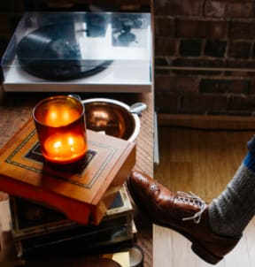 a candle lit on a table next to a pair of shoes