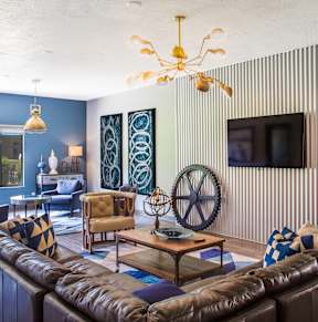 A living room with a brown leather couch and a chandelier.