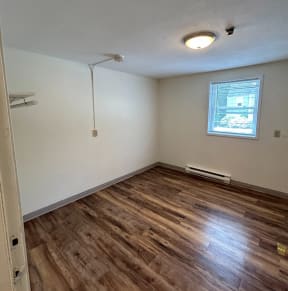 an empty room with hardwood floors and a window