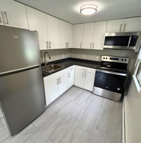 an empty kitchen with white cabinets and stainless steel appliances