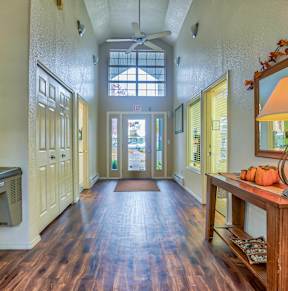 A hallway with a wooden floor and a table with a lamp on it.