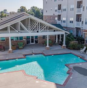 A pool with a pavilion in front of apartment buildings.