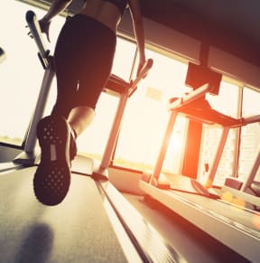 a woman running on a treadmill at the gym