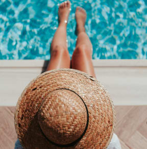 a woman with a straw hat laying by a pool
